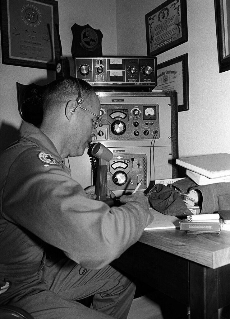 A radio operator speaking into a microphone at a communications station