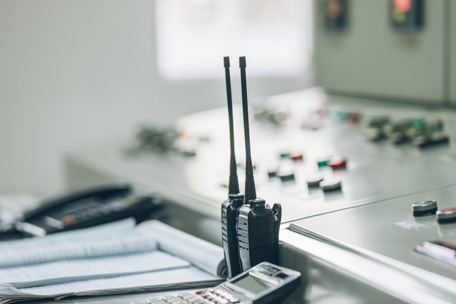 Handheld radio, telephone and logbook on a control room desk