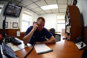 Coast Guard crewmember standing radio watch at a station console